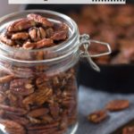 Jar of maple pecans with cast iron and text overlay