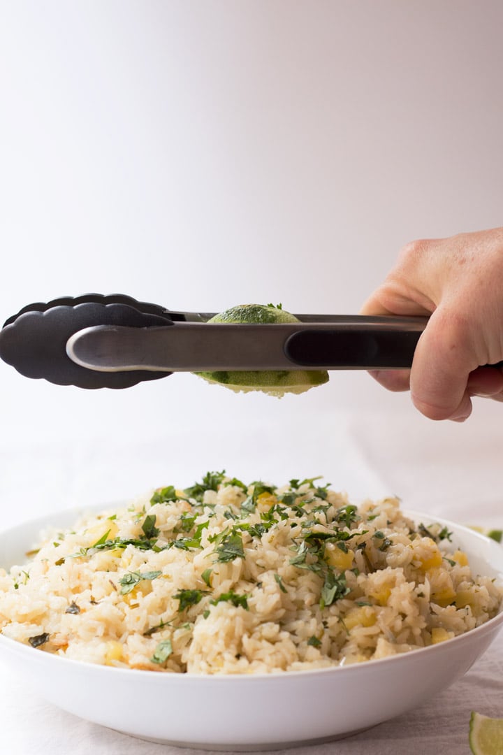 Squeezing lime with tongs on Pineapple Lime Rice