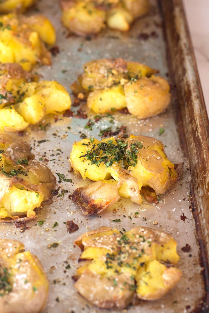 Edge of sheet pan with crispy smashed potatoes with herbs