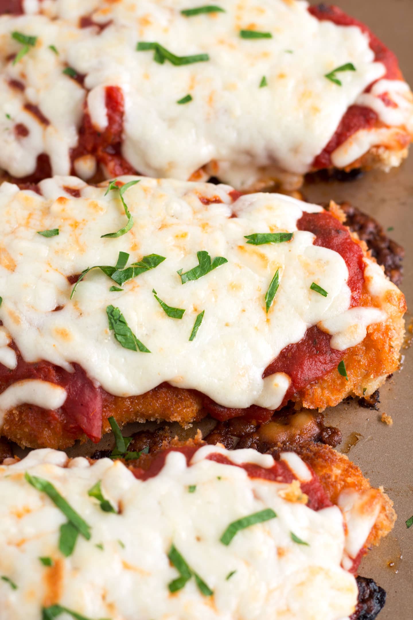 Pieces of Crispy Chicken Parmesan on sheet pan. 