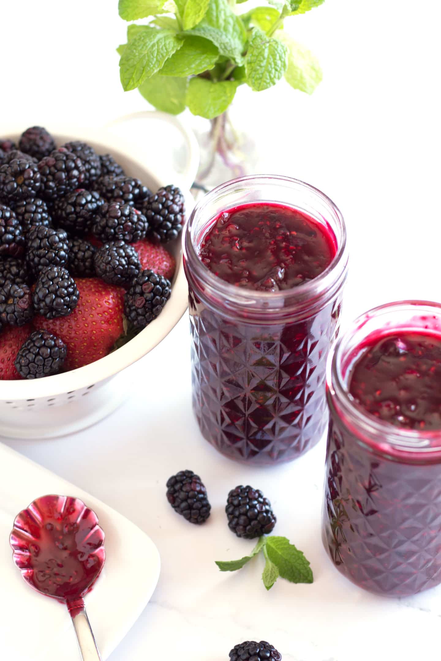 Jars of sauce with basket of fresh berries on side.