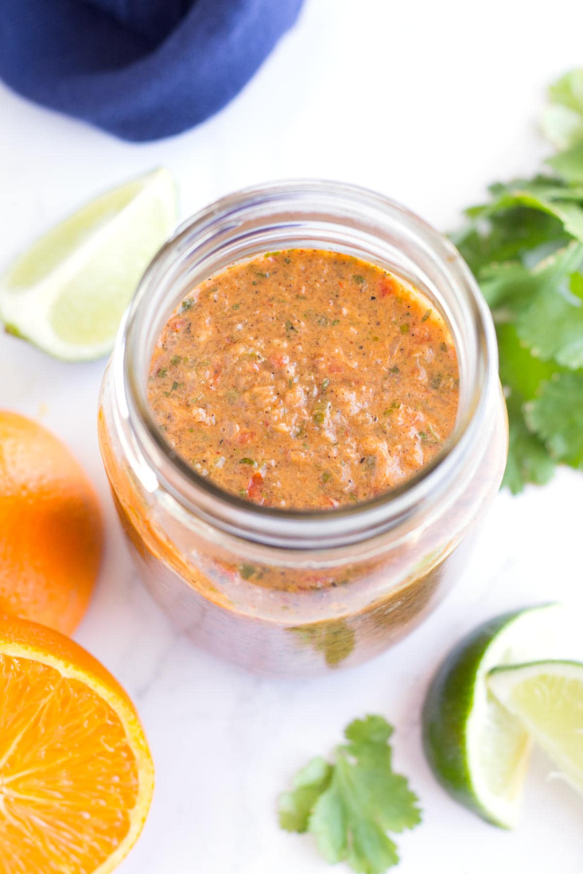 Jar of grilled taco marinade with oranges, limes, and cilantro on the counter