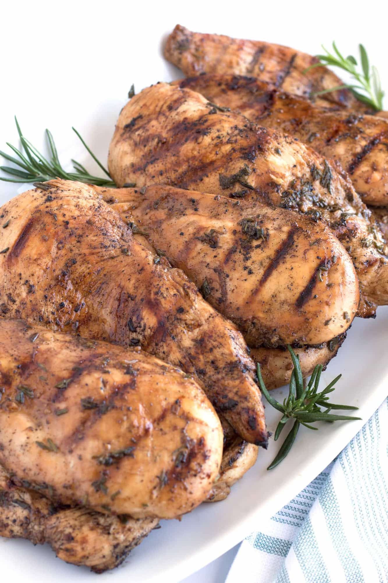 Full platter of grilled chicken with rosemary sprigs. 