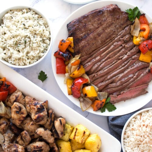 Grilled chicken, steak, and veggies with rice on platter.