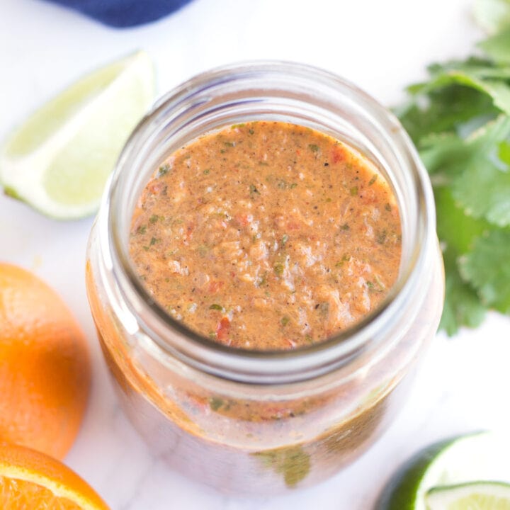 Jar of grilled taco marinade with oranges, limes, and cilantro on the counter