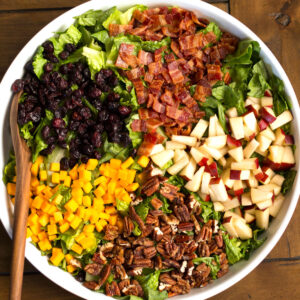 Pecans, cheese, cranberries, pears, bacon and lettuce in a bowl