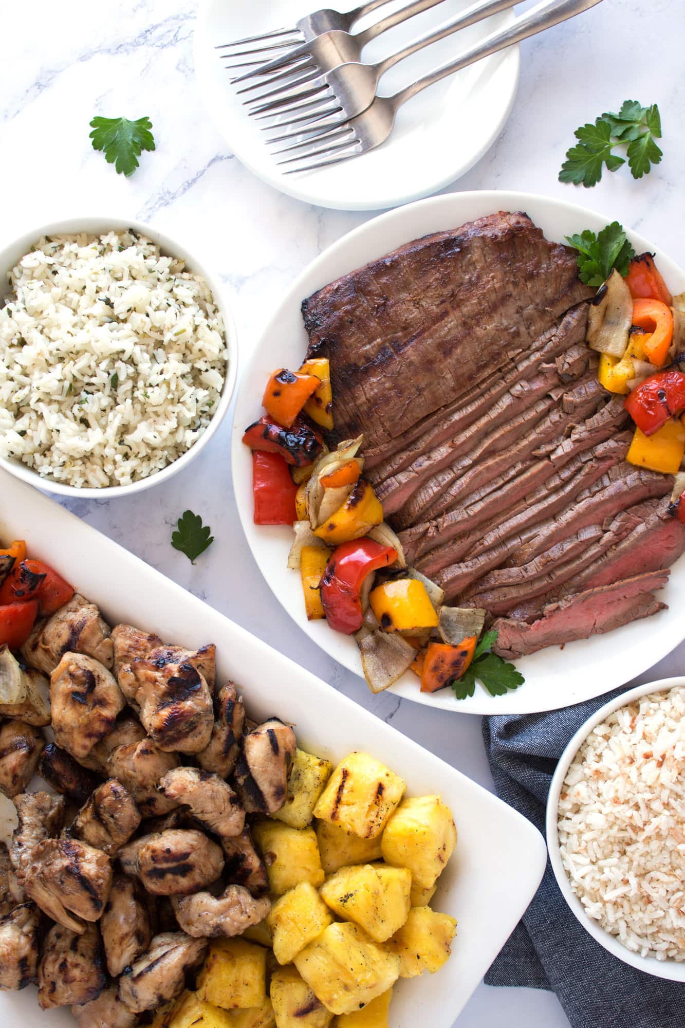 Grilled chicken, flank steak, vegetables, pineapple, and rice ready to be served.