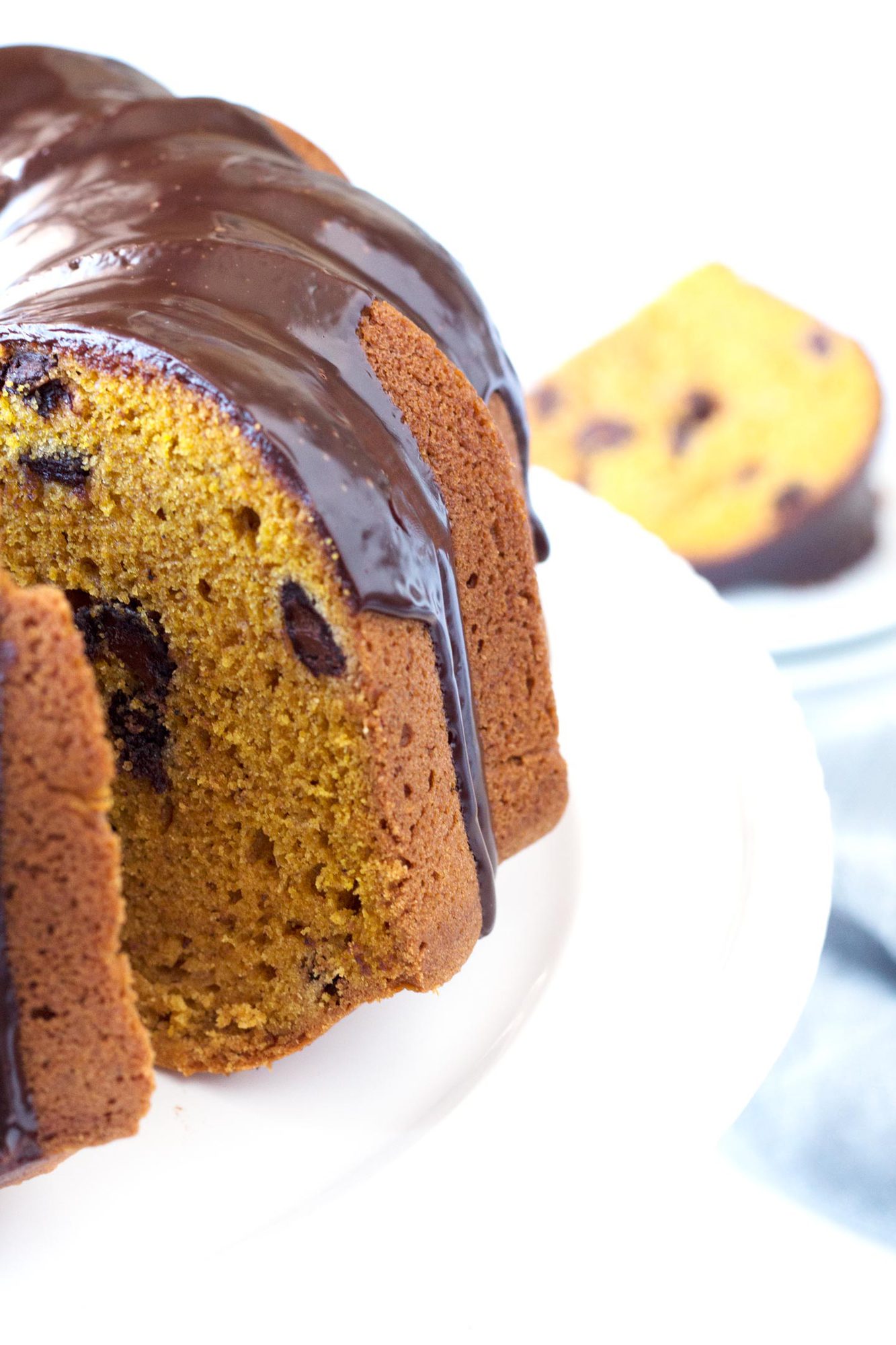 Pumpkin Bundt Cake with Chocolate Ganache on cake plate with slice removed