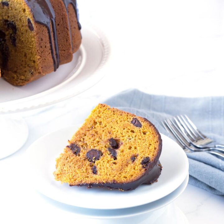 Slice of Pumpkin Chocolate Chip Bundt Cake on white plate with cake in background