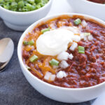 Up close view of chili in a bowl with toppings