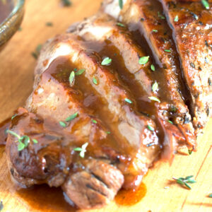 Sliced pork tenderloin with sauce on cutting board