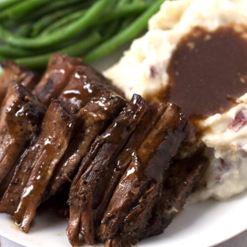Green beans, mashed potatoes, and pot roast on a plate.