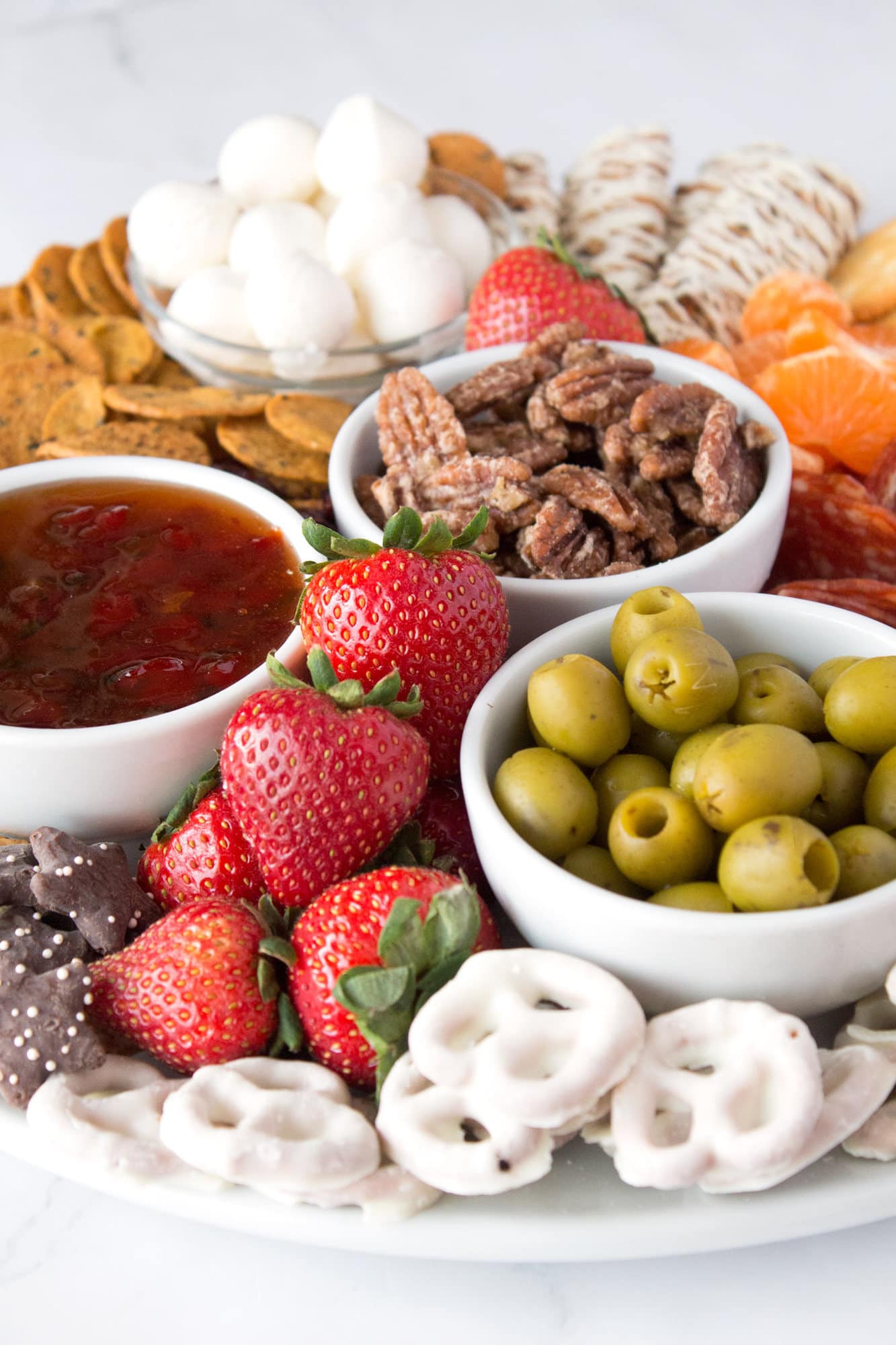 Berries, pretzels, olives, and other Christmas snacks on snack board.