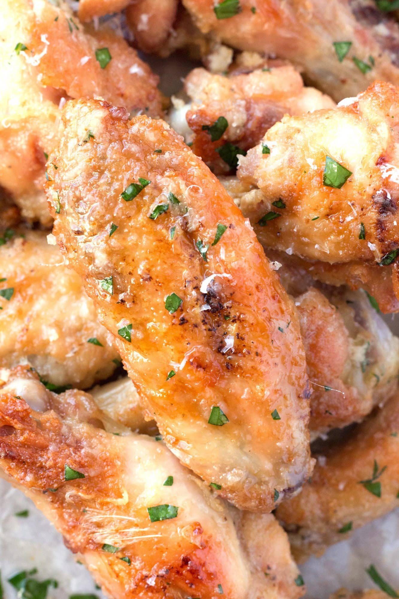 Up close golden brown garlic parmesan wings recipe on parchment paper.