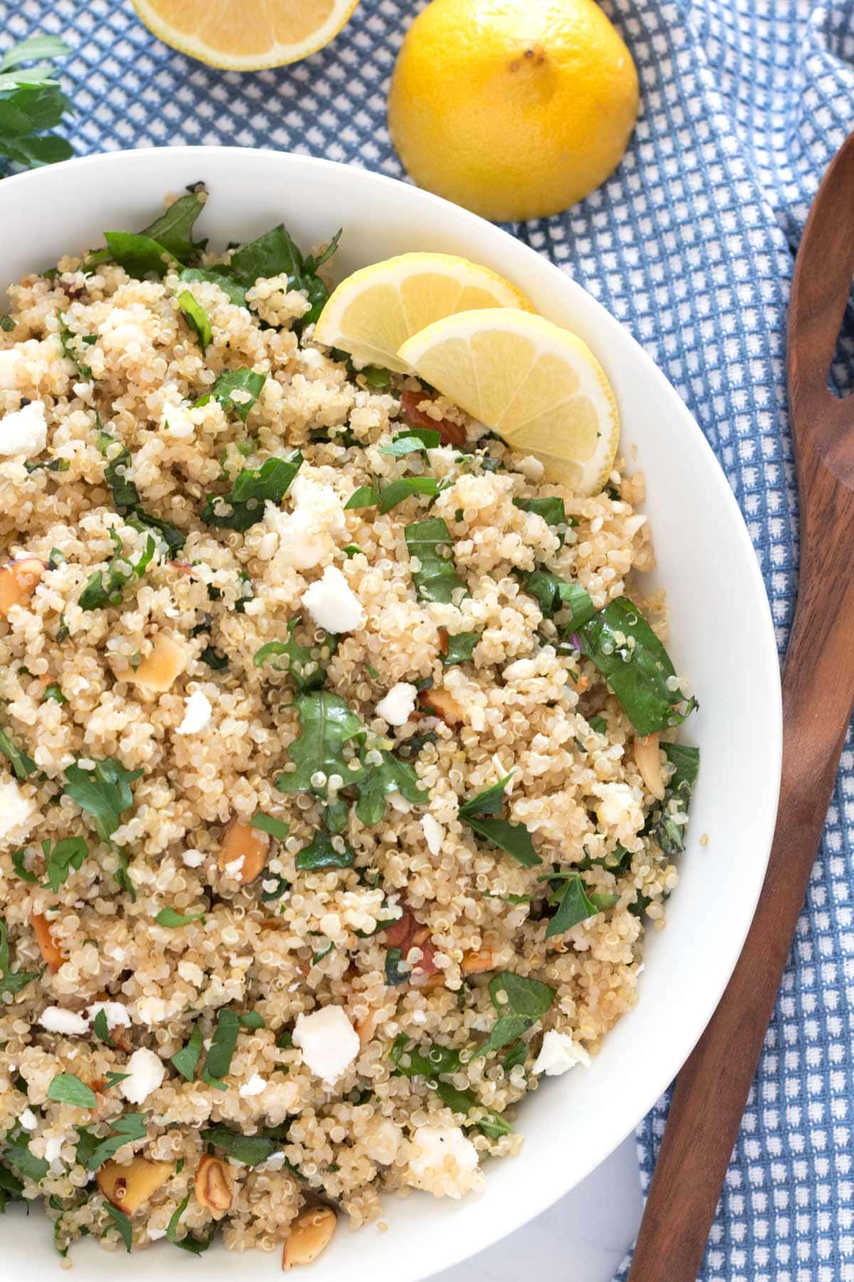 Overhead of healthy, cold quinoa salad in white serving bowl with blue towel underneath.