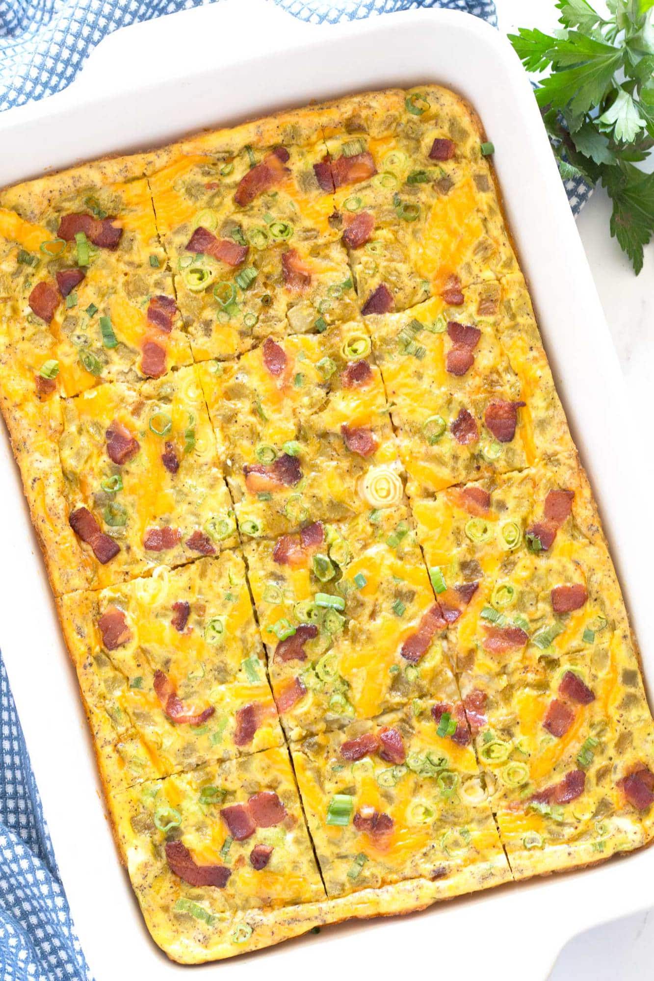 Pieces of breakfast casserole with bacon and green chilis in the baking pan.