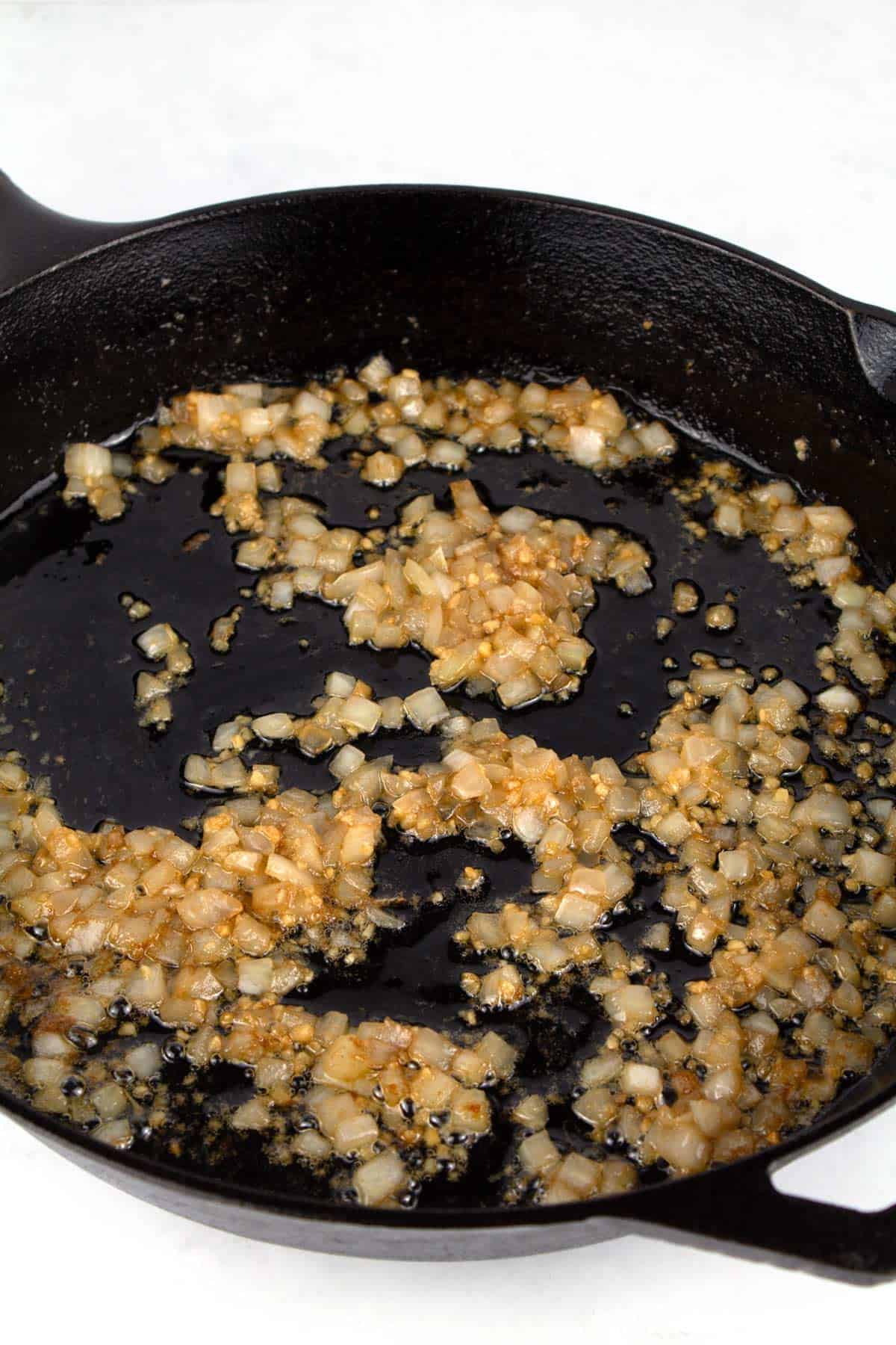 Cooking onions and garlic on the stovetop before adding in corn.