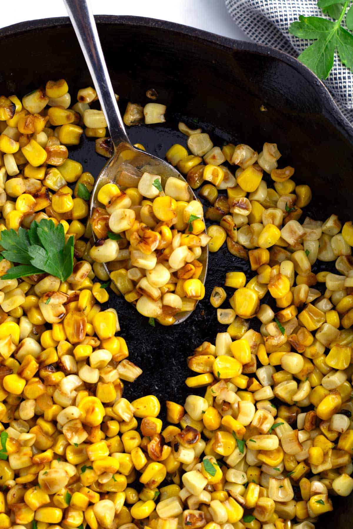 Skillet full of roasted corn with serving spoon.