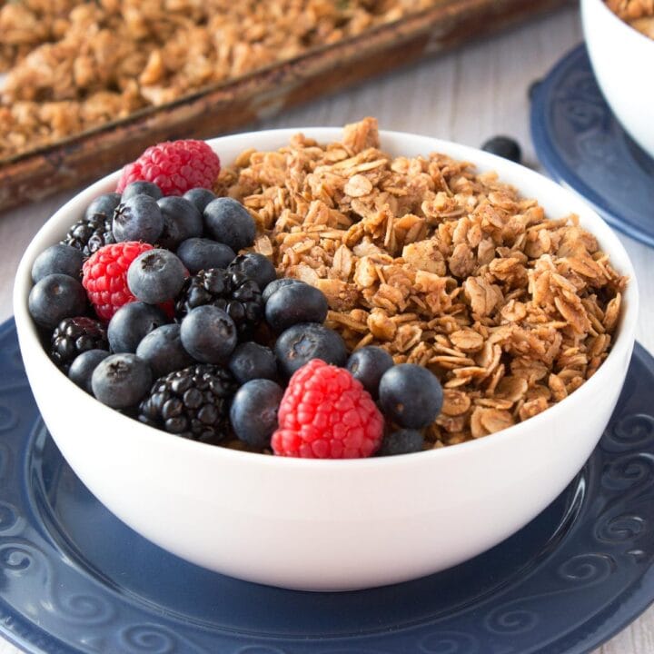 White bowl filled with granola and a mix of fresh berries.
