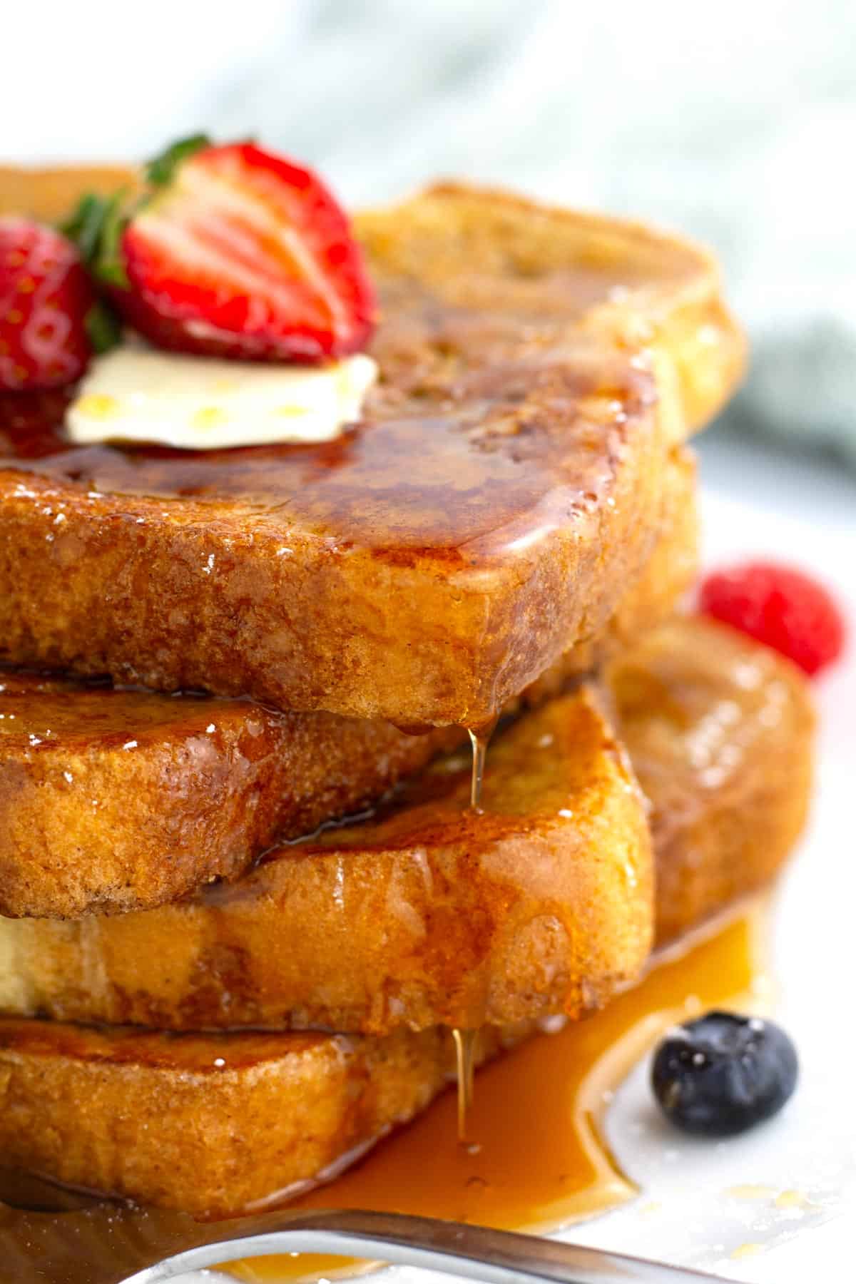 Maple syrup dripping off pieces of classic french toast.