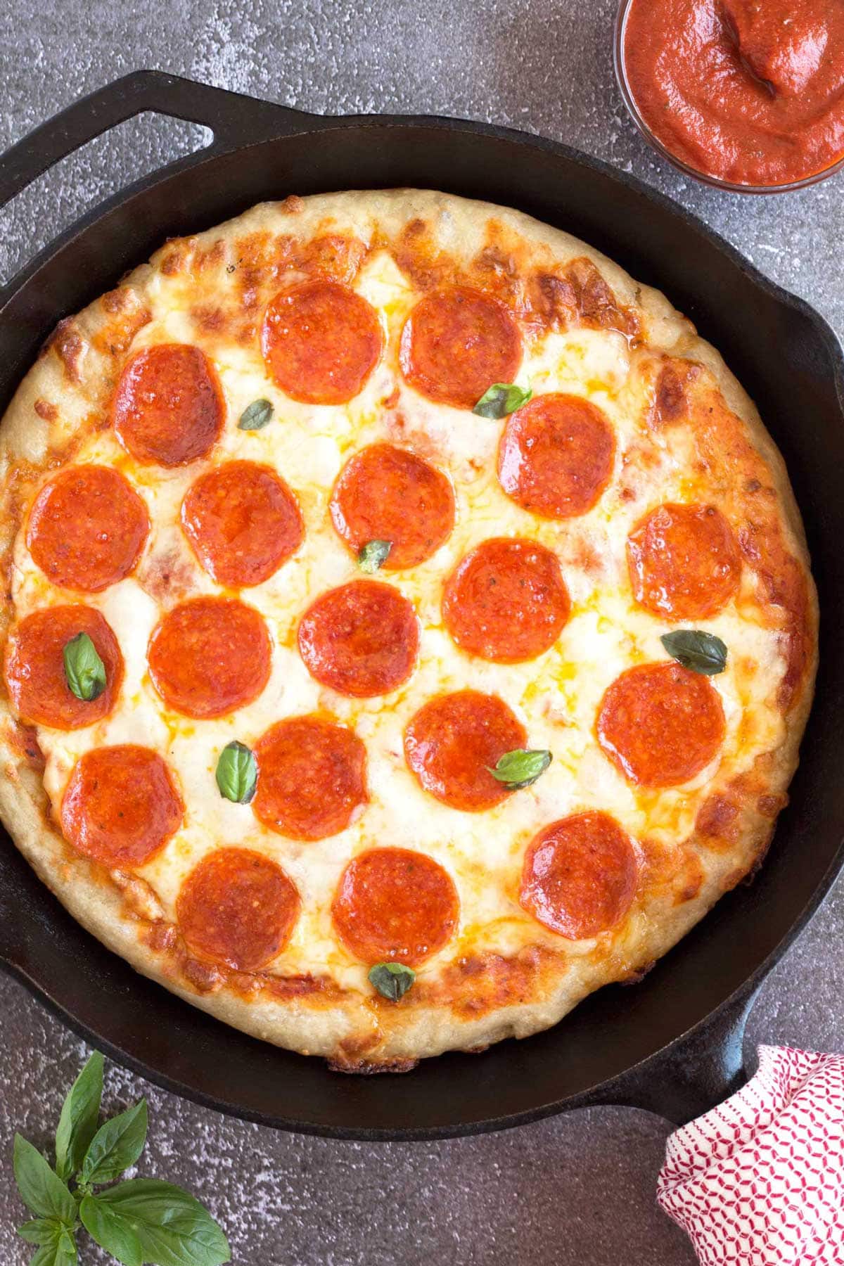 Pepperoni pan pizza in a 12-inch skillet with fresh basil.