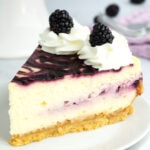 Slice of blackberry cheesecake with forks in background.