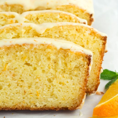 Staggered slices of moist orange loaf cake with glaze dripping off sides.