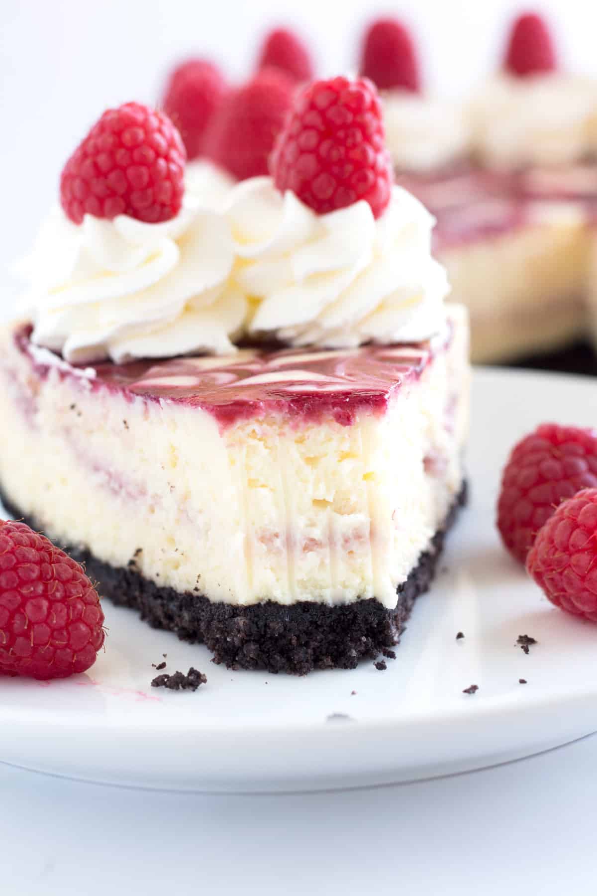 Bite removed from slice of white chocolate and raspberry cheesecake.