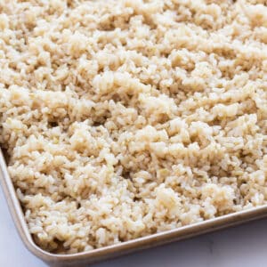 Brown rice spread onto a sheet pan.