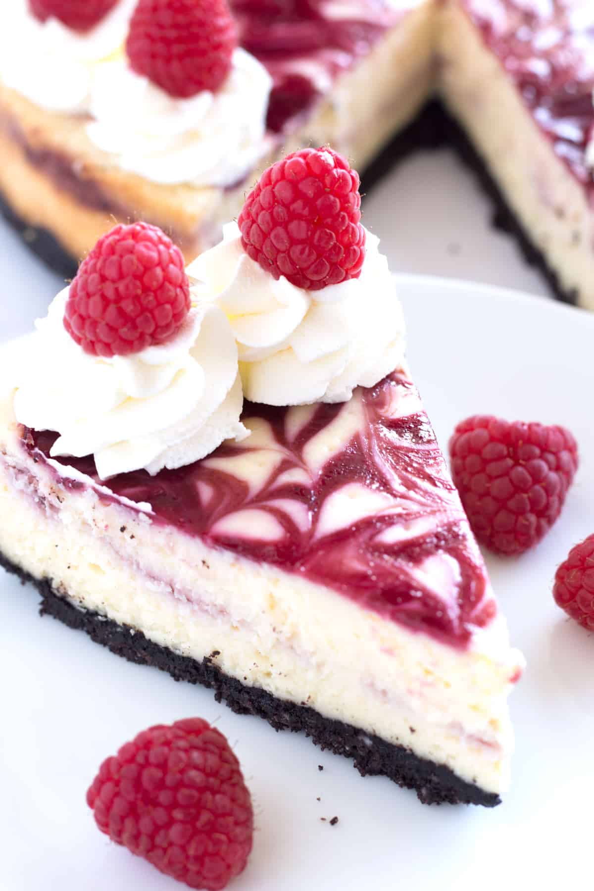 Slice of white chocolate cheesecake with raspberry swirl on top.