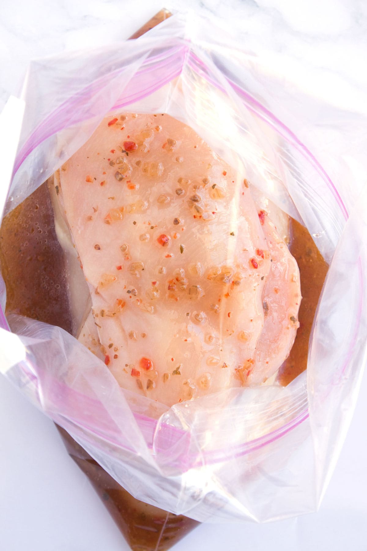 Overhead of 4-Ingredient marinade and chicken in a clear zipper bag.