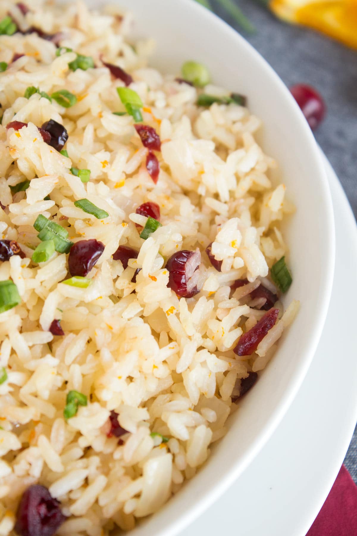 Super close view of orange rice with cranberries and green onions mixed in.