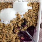 White baking dish with apple berry crisp and ice cream scoops and text overlay.