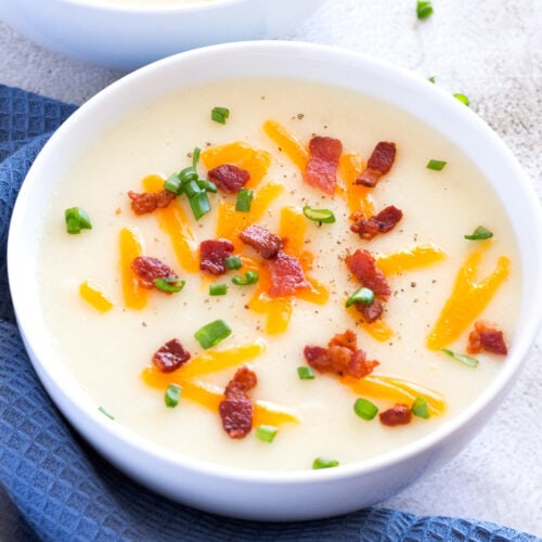 Potato Soup in a bowl with optional bacon, cheddar cheese, and green onion toppings.