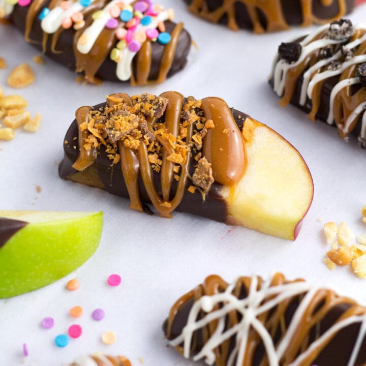 Caramel Apple Slices with different toppings on parchment paper.