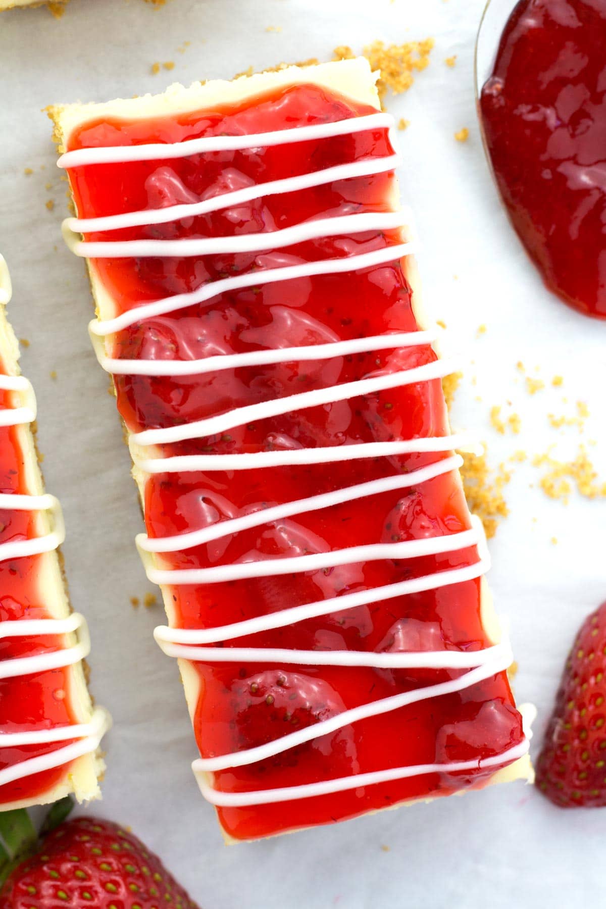 Up close Philadelphia strawberry cheesecake bars with chunky topping and white chocolate drizzle on top.