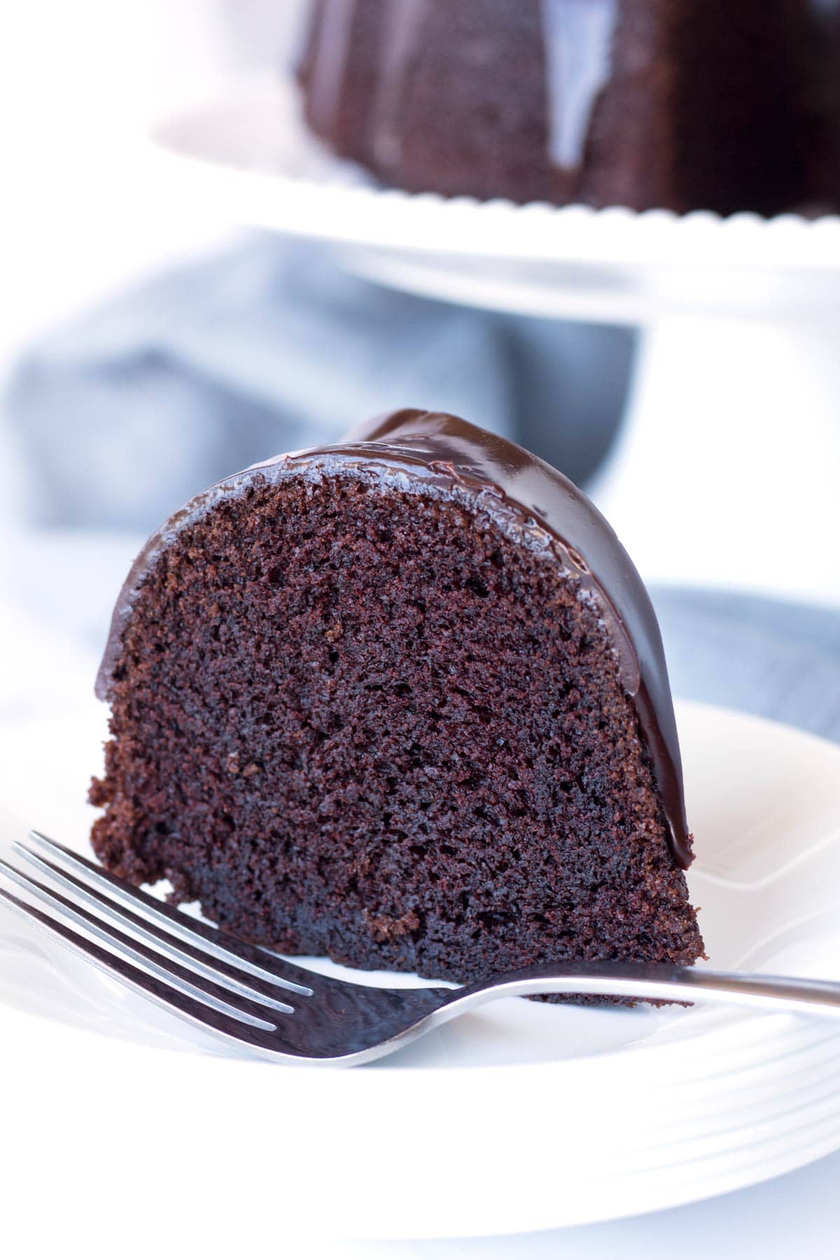 Extra moist chocolate Bundt cake with chocolate ganache on a plate.