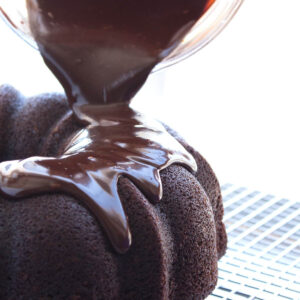 Pouring chocolate ganache on a bundt cake.