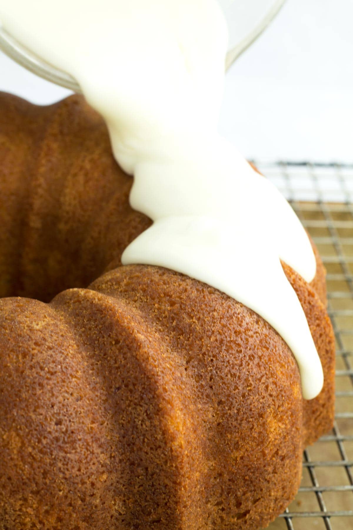 Pouring white chocolate frosting over the Bundt cake.