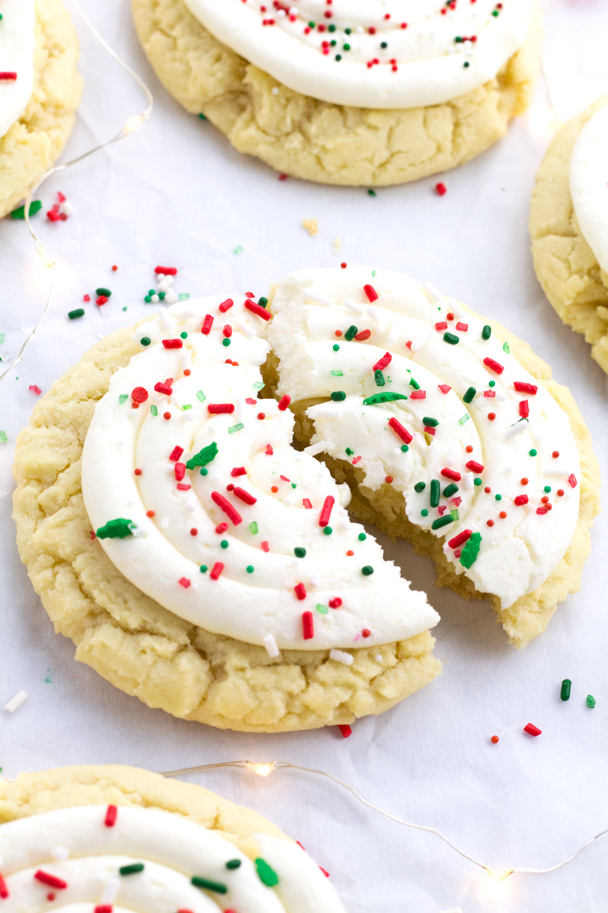 Copycat Crumbl cookies on parchment paper with Christmas sprinkles and twinkle lights.