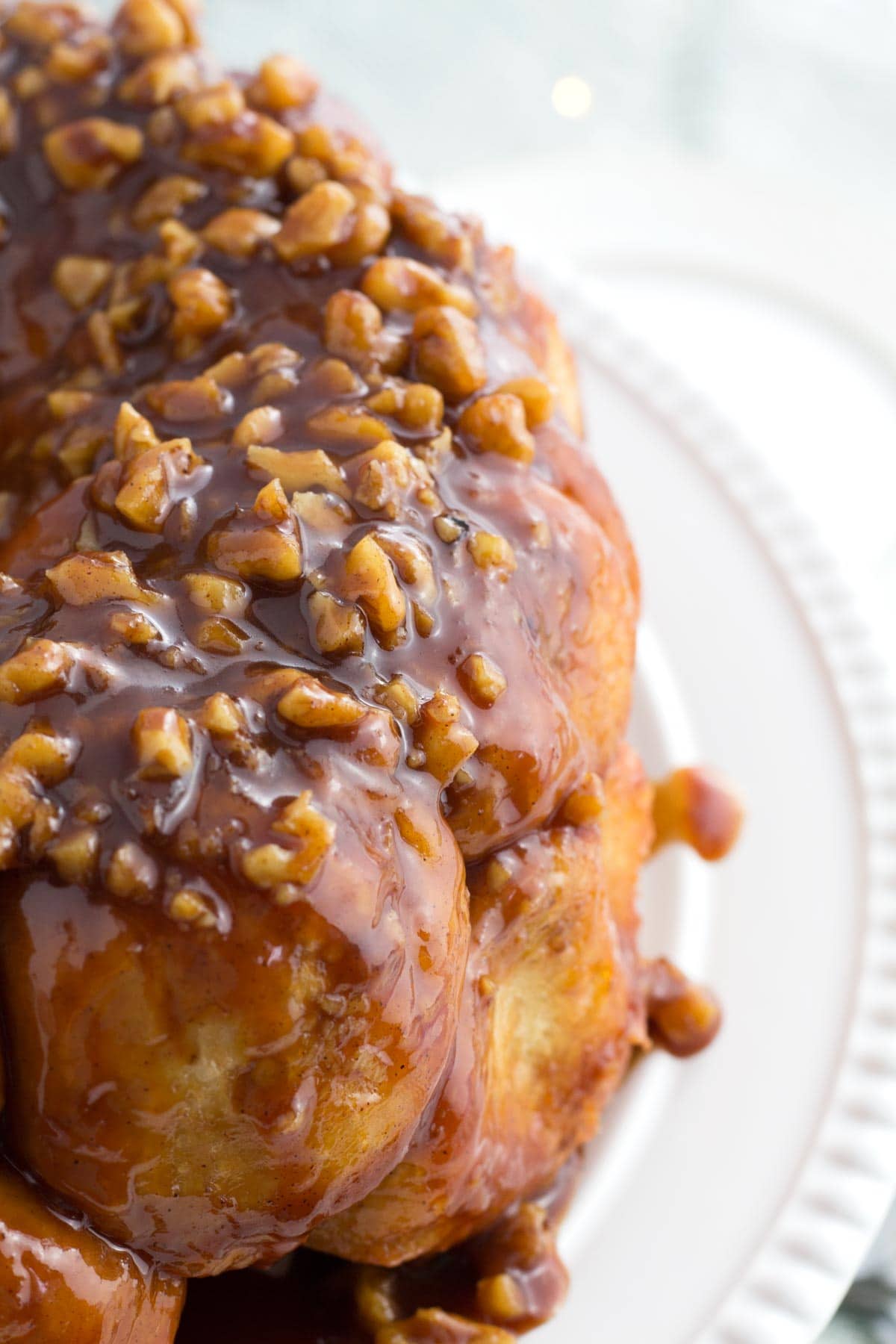 Monkey bread on cake stand with puddle of caramel sauce.
