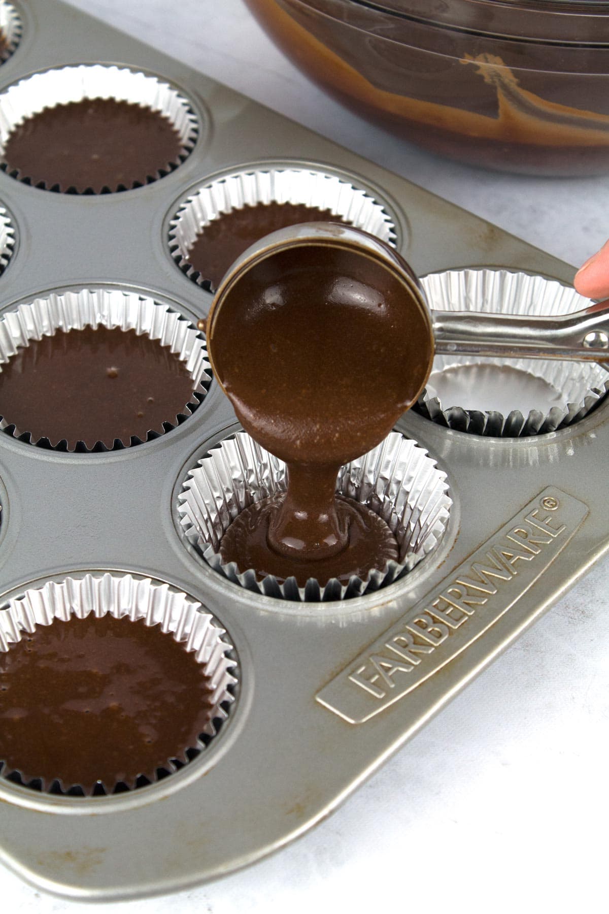 Pouring Christmas chocolate cupcake batter into muffin tin.