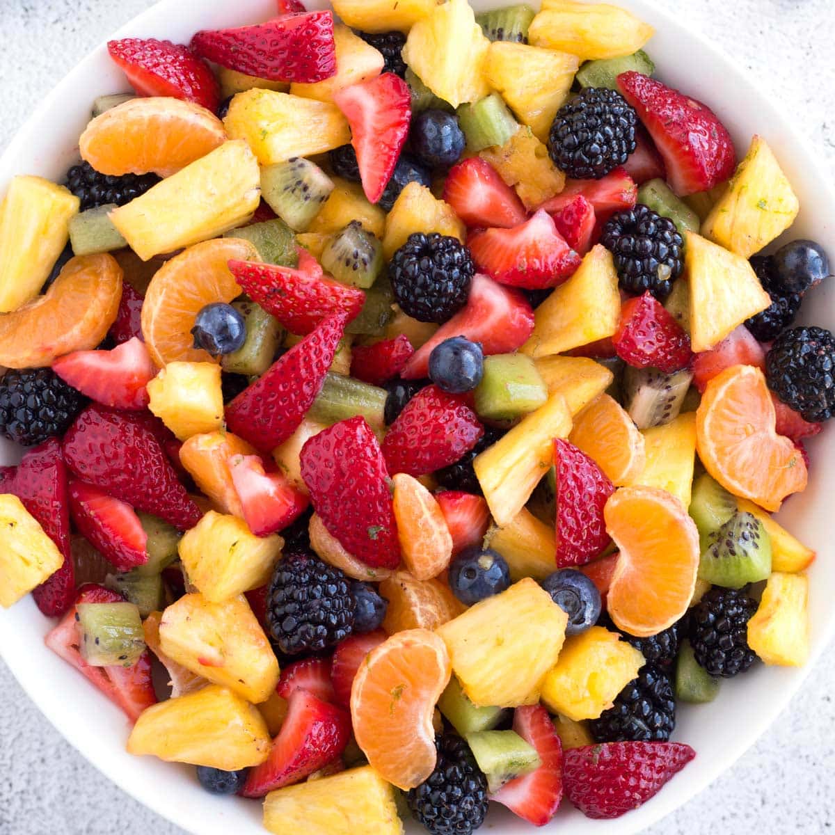 Fresh fruit tossed with dressing in a large bowl.