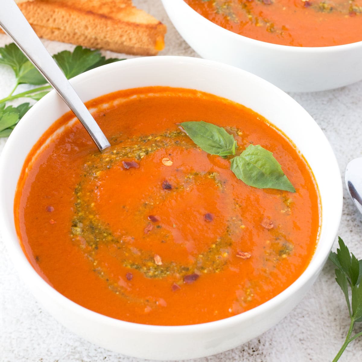 Tomato soup with basil pesto with spoon in the bowl.