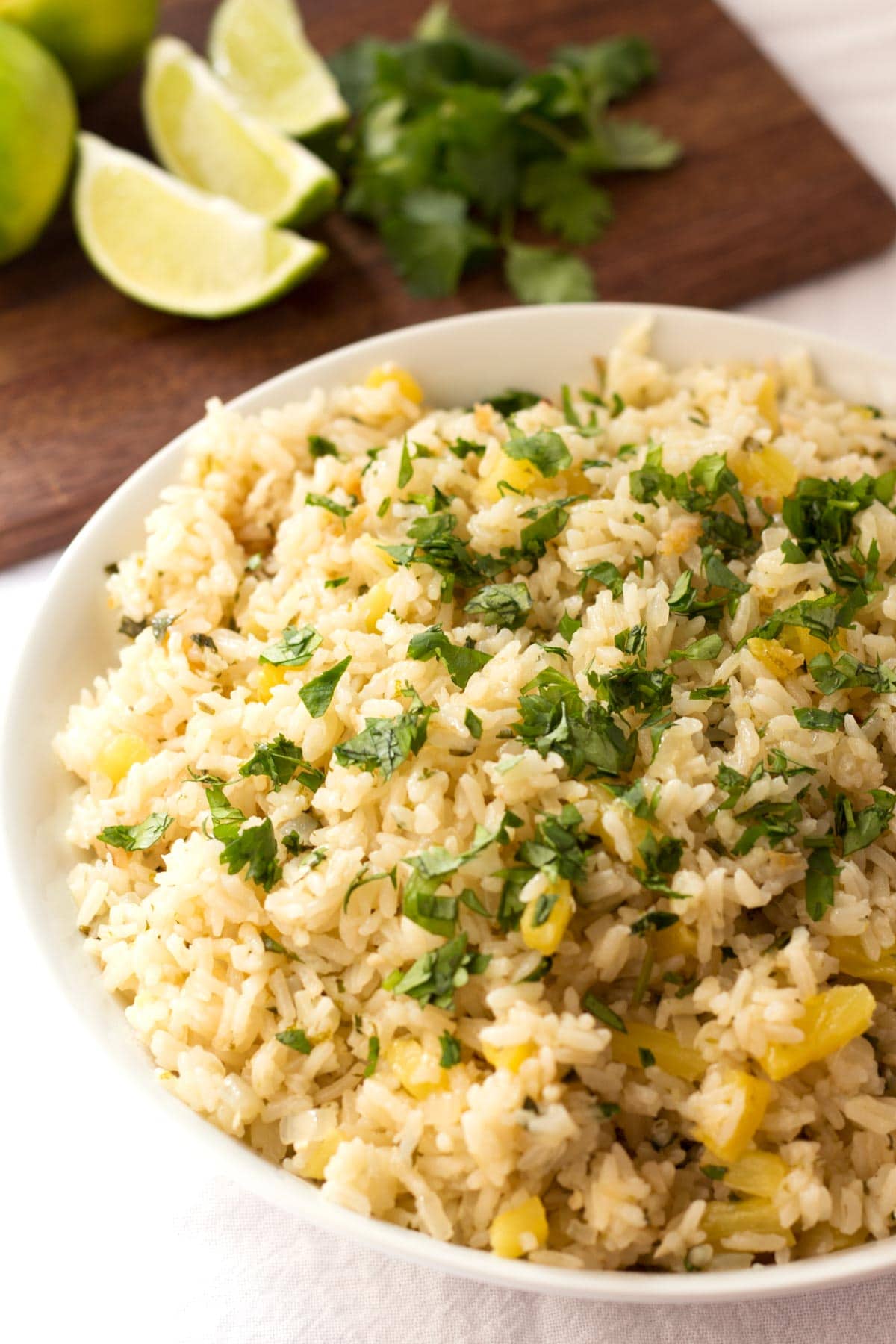 Close up of pineapple rice with extra limes and cilantro in the background.