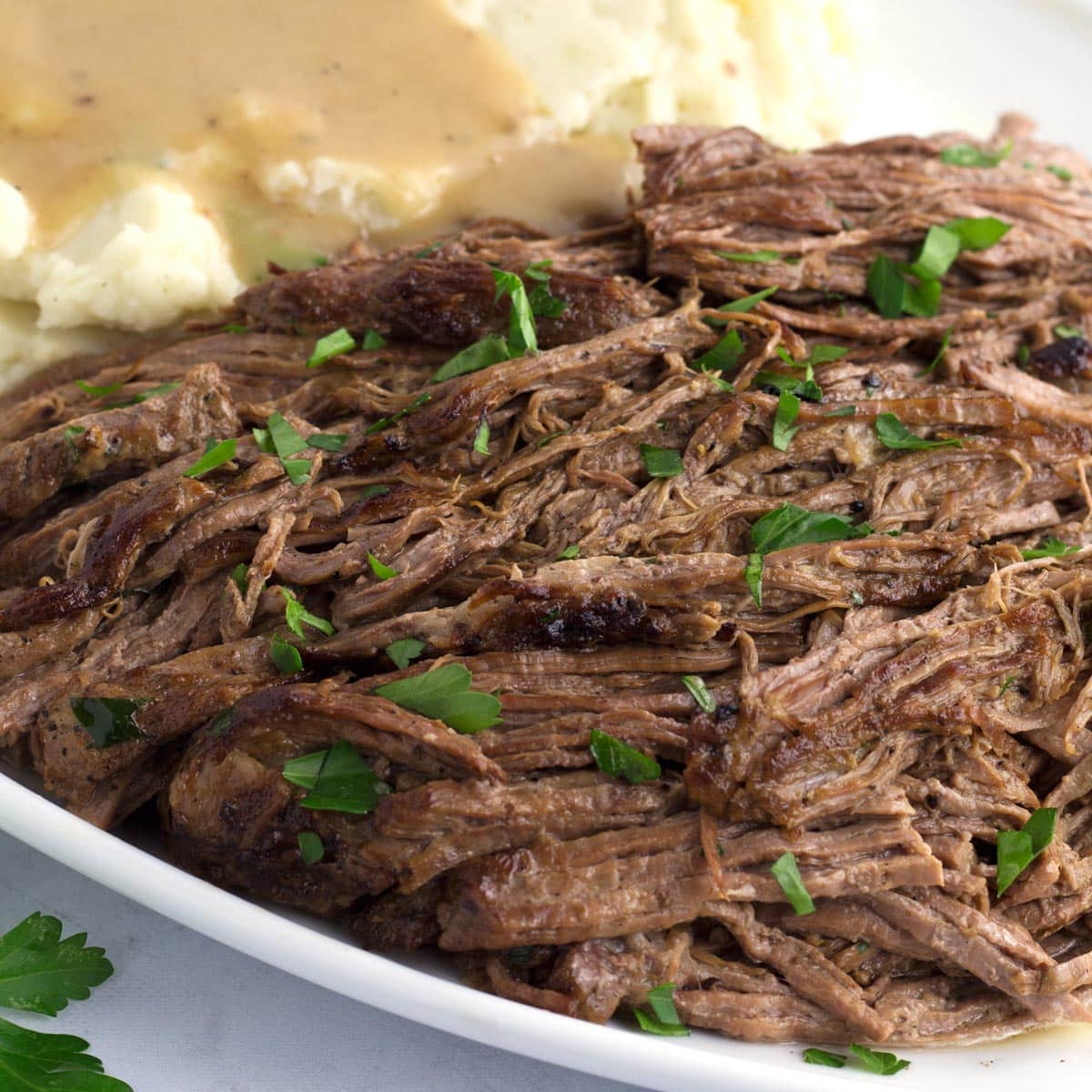Serving platter of tri tip roast with mashed potatoes and creamy gravy. 