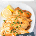 White oval platter of lemon chicken breasts with text overlay.