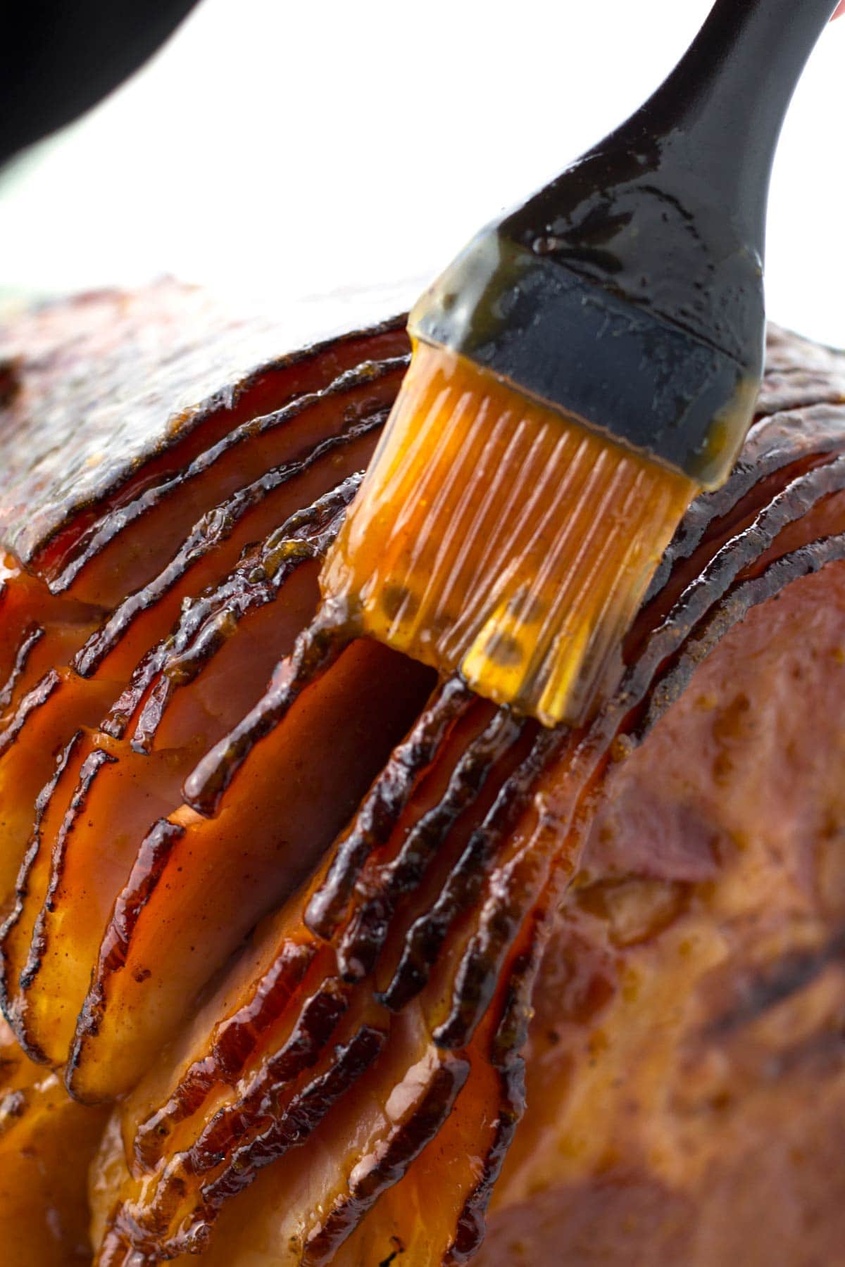 Brushing pineapple brown sugar glaze on ham in roaster.