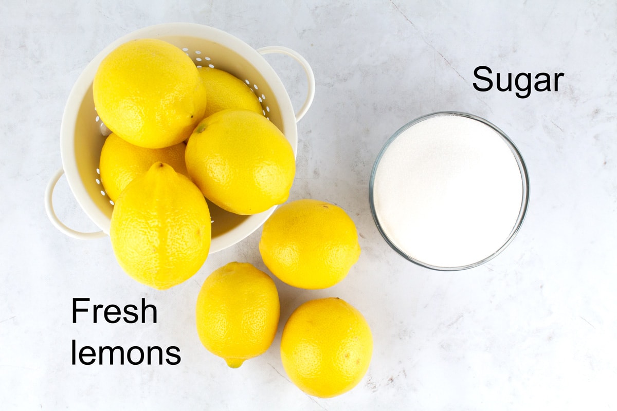 Overhead view of a pile of lemons and a bowl of white sugar with text labels.