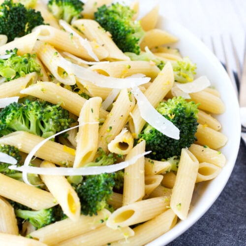 Lemon broccoli pasta in a white bowl with a gray towel underneath.
